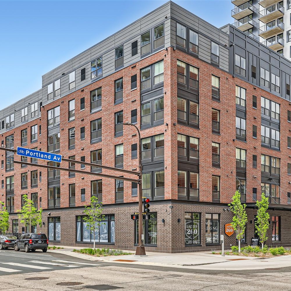 The exterior view of Ladder 260, a modern apartment building with brick and metal facade at the corner of Portland Avenue.