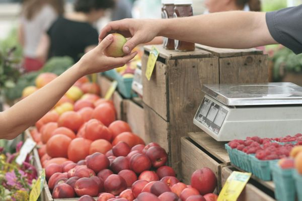 Close up of a fruit being handed over at a farmer's market