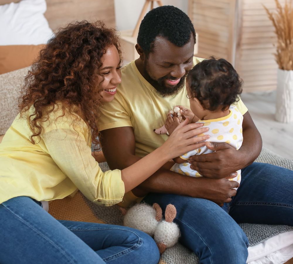 Happy parents wearing yellow shirts and jeans holding baby