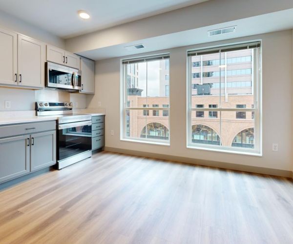Ladder 260 studio apartment with large windows, wood-like flooring, and modern kitchen