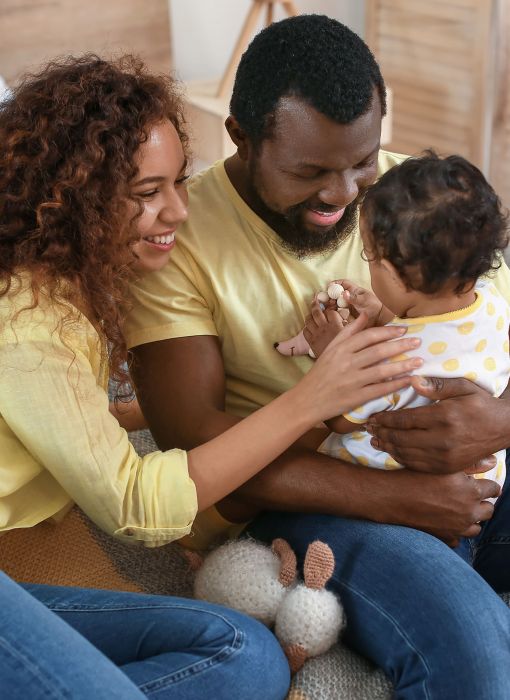 Happy parents wearing yellow shirts and jeans holding baby