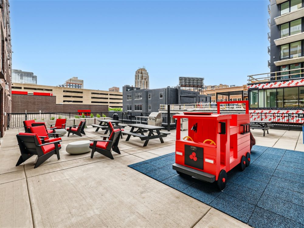 The outdoor deck of Ladder 260 with red and black patio furniture, picnic tables, and a children's play area.