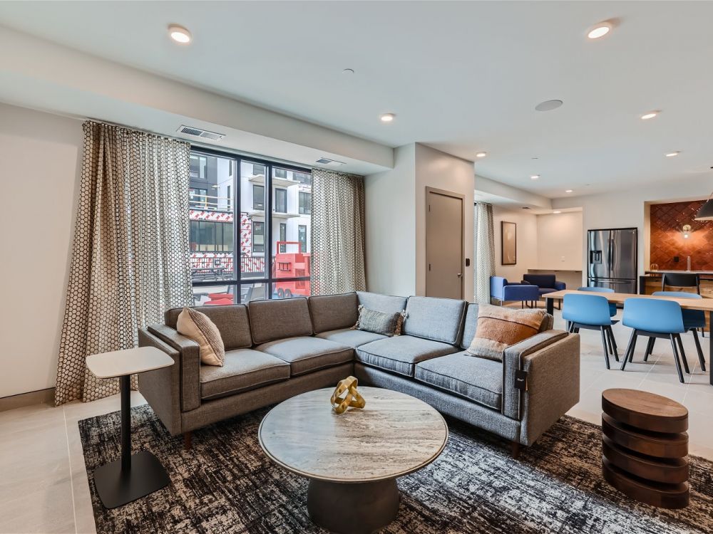 The club room at Ladder 260 with a comfortable gray sectional sofa, coffee table, and dining area.
